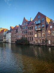 Fototapeta premium Gent, Belgium - December 27,2025: Traditional brick and stone architecture buildings along a canal in sunset