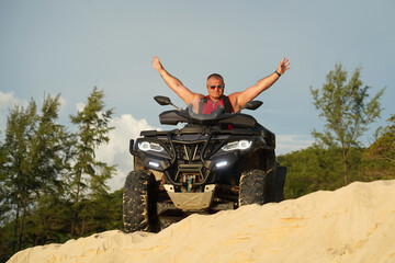 Fototapeta premium A man engages in extreme ATV riding on sand beach early in the morning