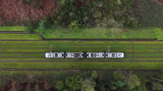 Eletrical subway riding on the tracks with grass. Sustainable public transportation top down view.