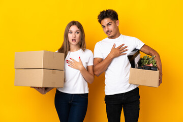 Teenager couple moving in new home among boxes isolated on blue background surprised and shocked while looking right