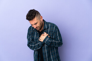 Caucasian man isolated on purple background having a pain in the heart
