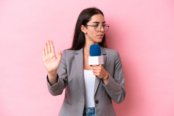 Naklejka premium Young caucasian tv presenter woman isolated on pink background making stop gesture and disappointed
