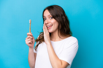 Obraz premium Young caucasian woman brushing teeth isolated on blue background whispering something