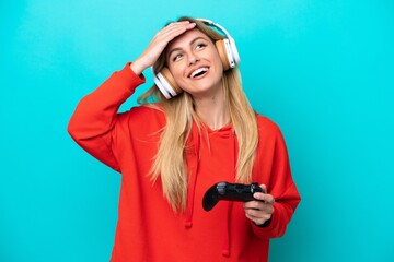 Young Uruguayan woman playing with a video game controller isolated on blue smiling a lot