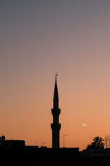 Obraz premium Minaret silhouette against a vibrant orange sunset sky