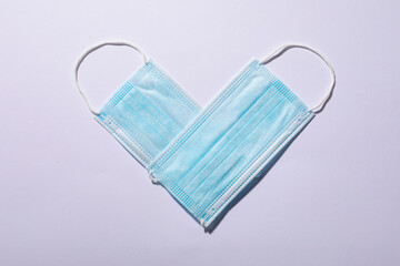 Overhead view of protective face masks arranged in heart shape on white background, copy space © wavebreak3