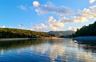 Naklejka premium Scenic sunset landscape of Sukko Lake with forested hills and blue sky reflections in the water. Anapa, Russia. 