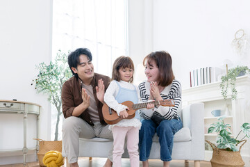 A child enjoys playing a ukulele with their parrent