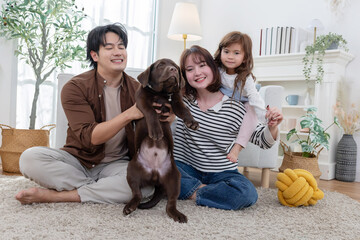 Family plays with dog at home during the day in a cozy living room