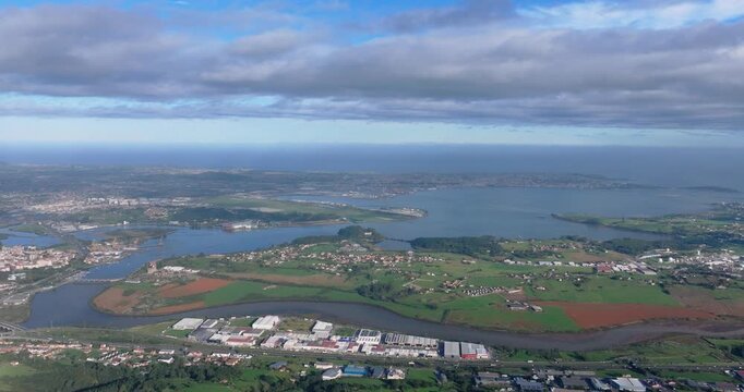High altitude drone panorama of Spanish countryside near Santander showing farmland, distant water bodies and dramatic layered cloud cover