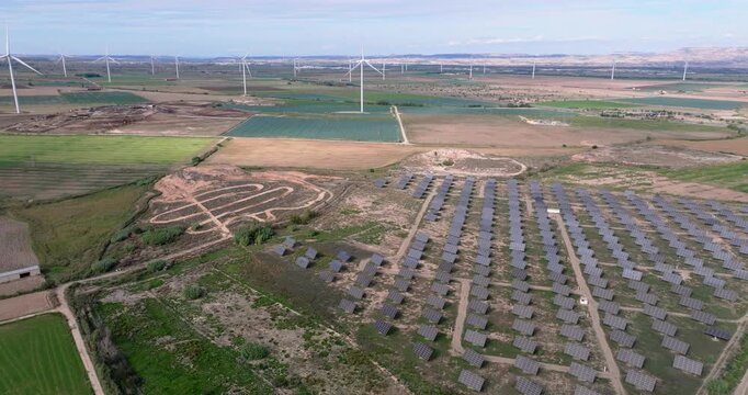 Drone flyover across massive Spanish solar installation with repeating panel grids, access tracks and distant farmland stretching to the horizon