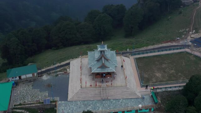 Rare slow dynamic drone orbit unveils Hatu Mata Temple's green-roofed complex, circling to expose enveloping dense forests, paths, and misty hilltops eventually reaches beautiful horizon.