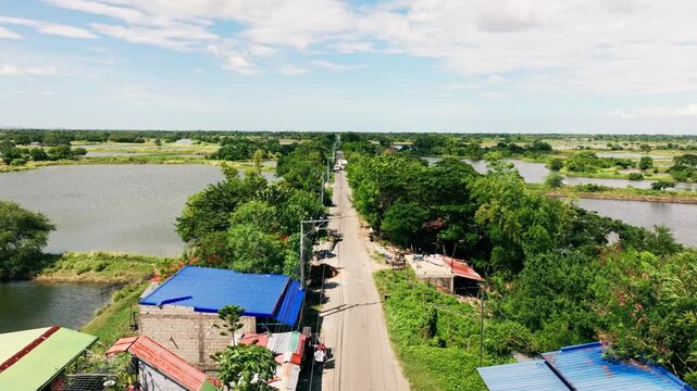 Drone flies forward, sunny rural road in Lingayen Pangasinan with white truck