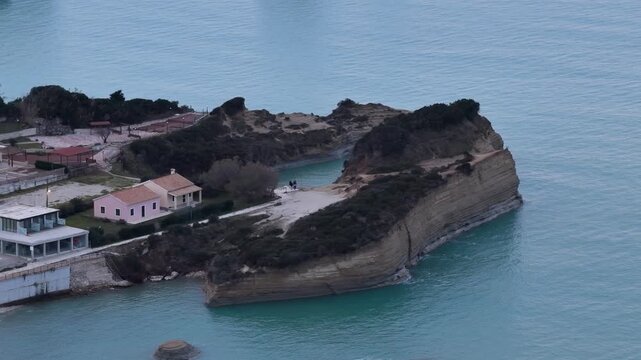etailed aerial drone shot of tourists walking on the layered sandstone cliffs of Canal d'Amour in Sidari, Corfu, Greece, showcasing the unique geological erosion, coastal vegetation