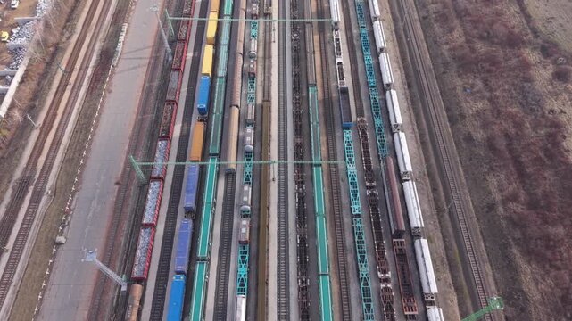 Top-down aerial view of a busy railway yard with multiple freight trains positioned on parallel tracks. The video illustrates large-scale rail transport, cargo handling, and logistics infrastructure.