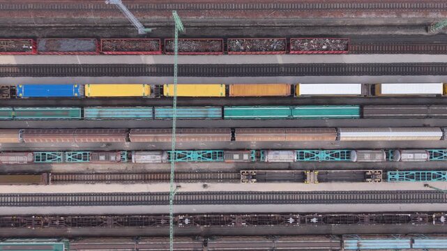 Top-down aerial view of a railway freight yard with parallel tracks filled with colorful cargo wagons and freight trains.