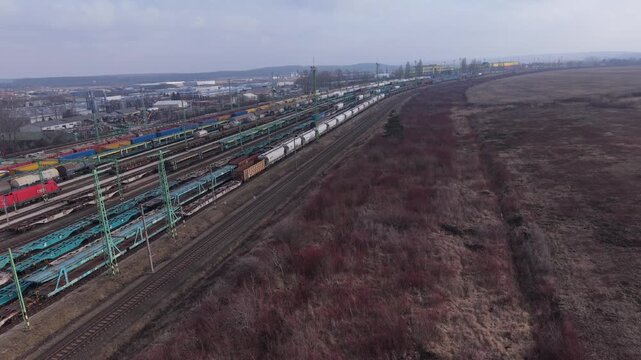 Aerial view of a busy freight railway yard with long cargo trains arranged on multiple parallel tracks.