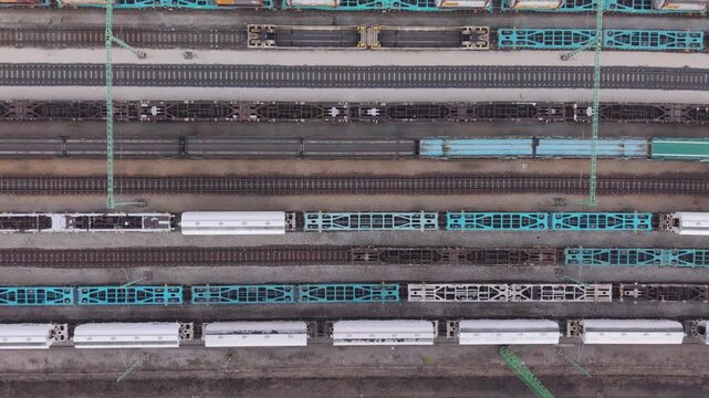 Top-down aerial view of a large railway freight yard with parallel tracks and stationary cargo wagons arranged in repeating patterns.