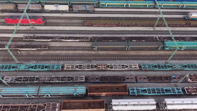 Top-down aerial view of an industrial freight railway yard showing multiple cargo wagons and trains aligned on parallel tracks.