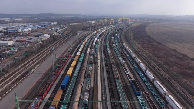 Aerial view of a railway yard filled with freight trains and cargo wagons aligned on parallel tracks. The video represents modern rail transport, logistics operations, and cargo distribution.