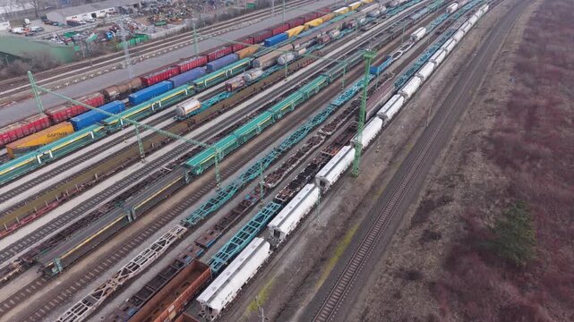 Aerial view of a large industrial freight railway yard with multiple cargo trains on parallel tracks.
