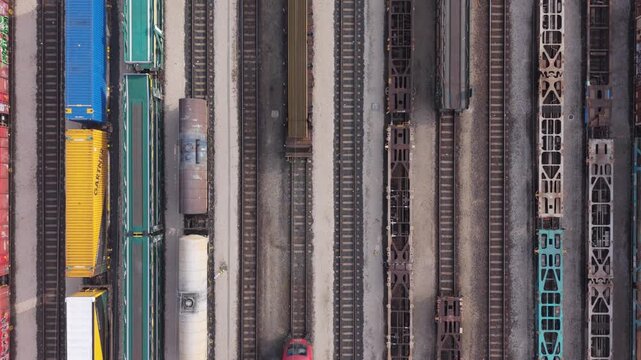 Top-down aerial view of multiple freight trains standing on parallel railway tracks in an industrial rail yard.