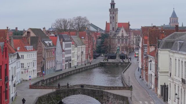 Aerial reveal shot starting from King's Bridge (Koningsbrug) to the Jan Van Eyck sculpture and the historic Burghers&rsquo; Lodge (Poortersloge) in Bruges, Belgium. Medieval architecture and canal view