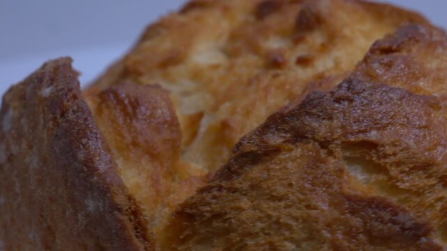 fresh, crusty bread rolls rotate slowly on a white plate in a studio, highlighting their golden-brown texture and artisanal appearance in a close-up shot.
