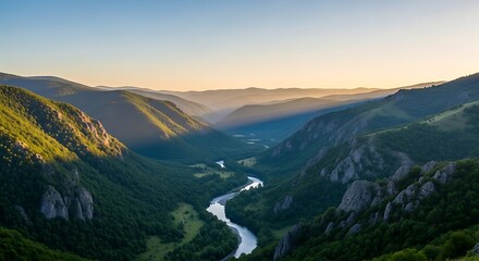 Naklejka premium Wide valley with winding river and sunlit green mountains at dawn nature landscape