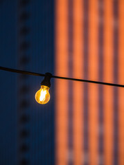 Bulb lamp shines in foreground with Karlatower standing tall in Gothenburg at twilight