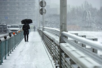 雪の日に橋を渡り通勤する人