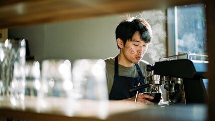 Male barista brewing fresh espresso with rising steam in a modern cafe