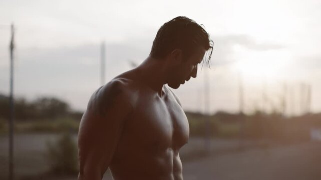 Man lifts dumbbells during sunset workout in outdoor area focusing on fitness and strength training