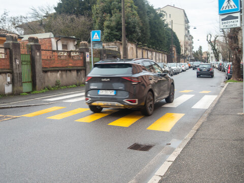 Modern Kia Sportage SUV navigating a city street crosswalk with parked cars, capturing urban mobility and European automotive compliance
