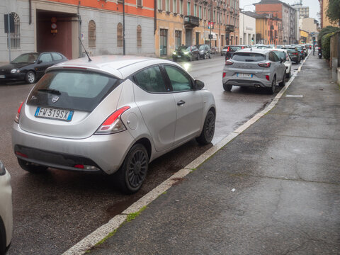 Silver Lancia Ypsilon and Ford Puma navigating wet city street during a rainy day traffic commute in Italy
