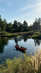Man in panama fishing in inflatable boat, drifting slowly on river on sunny summer day. Travel, outdoor recreation, rafting, vacation, outdoor activities