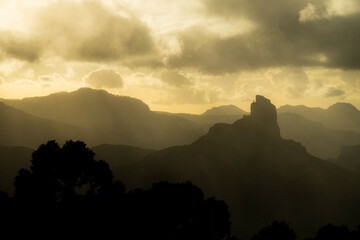Golden hour clouds above distant mountain ridges with deep silhouettes, horizontal composition © Stoca