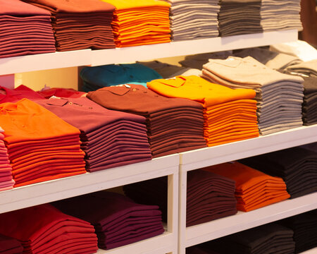 Various color shirts at shelf in shop background