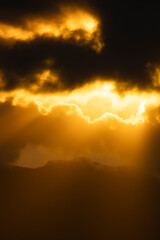 Glowing clouds with golden light above mountains Vertical © Stoca