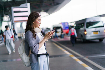 Woman traveler standing at airport pickup and drop off area while using a smartphone. © DG PhotoStock