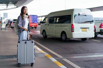Asian woman traveler waiting with suitcase at airport pickup area © DG PhotoStock