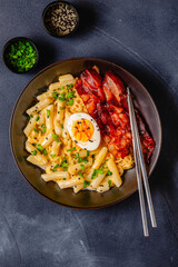 Korean street food - creamy rapokki served with bacon and egg.