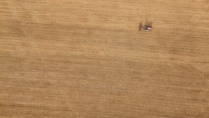 Fototapeta premium Vintage crawled tractor is smoothing plowed soil in a vast, brown field, showcasing agricultural work and sustainable farming practices in the rural Italian landscape