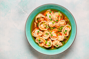 Dumplings served in a bowl with broth and green onions.