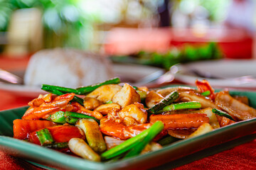 Delicious stir-fried vegetables with chicken served on a plate at a vibrant outdoor restaurant