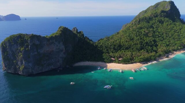 Aerial view of Helicopter Island (Dilumacad) in El Nido, Palawan. Tropical limestone cliffs, white sand beach and outrigger boats in the turquoise sea of the Philippines