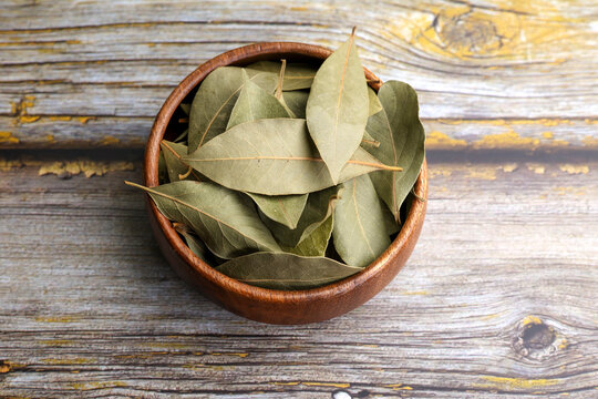 Defne yaprağı Dried bay leaves in a bowl on a wooden background.