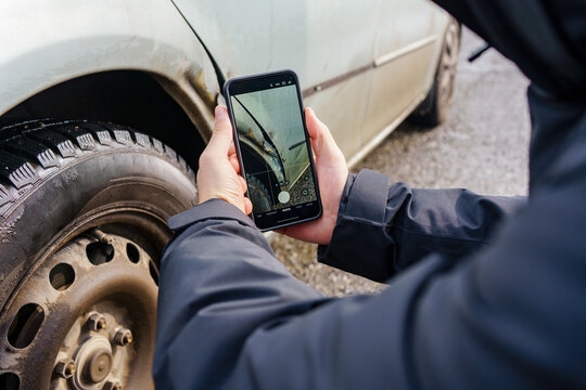 Close-up of a smartphone photographing scratches and dents on a silver car fender. Image shows documenting vehicle damage for inspection or repair purposes.