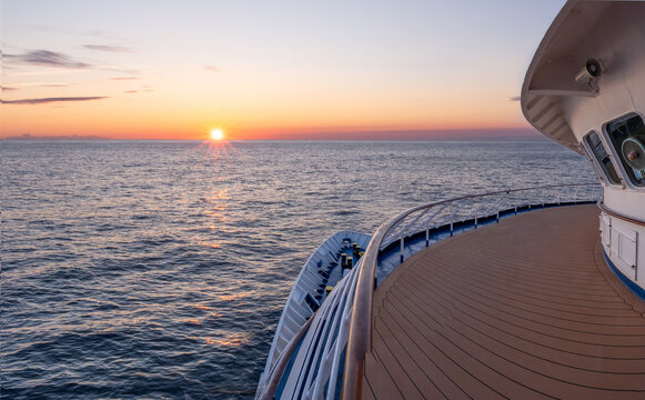 Kreuzfahrt bei Sonnenaufgang auf hoher See, Blick vom Schiffsdeck &uuml;ber den Bug auf den Ozean, maritime Urlaubsreise in der goldenen Stunde, Entspannung und Freiheit auf dem Wasser