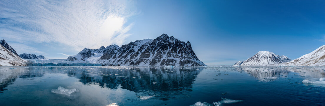 Spitzbergen, Svalbard, Norwegen: Arktische Gebirgslandschaft spiegelt sich im stillen Wasser des Magdalenefjorden mit Treibeis unter strahlend blauem Himmel.
